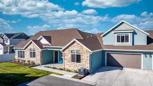 View of front of home with a garage, a front yard, and central AC