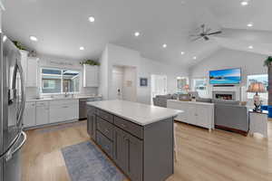 Kitchen featuring white cabinetry, appliances with stainless steel finishes, plenty of natural light, vaulted ceiling, and a center island