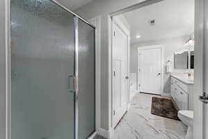 Bathroom with a shower with door, vanity, and toilet