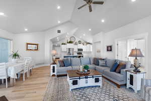 Living room with a wealth of natural light, ceiling fan, light wood-type flooring, and lofted ceiling