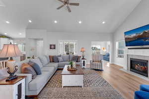 Living room featuring light wood-type flooring, ceiling fan, and high vaulted ceiling