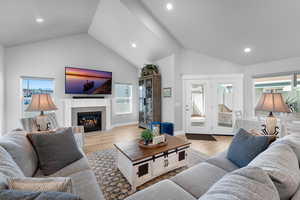 Living room featuring light wood-type flooring, vaulted ceiling, and plenty of natural light