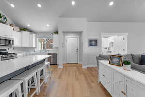 Kitchen featuring white cabinetry, a kitchen bar, light hardwood / wood-style floors, and stainless steel appliances