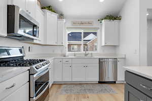 Kitchen featuring white cabinetry, sink, light wood-type flooring, and appliances with stainless steel finishes