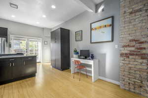 Home office with beamed ceiling, french doors, built in desk, and light hardwood / wood-style floors