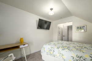 Carpeted bedroom with a closet and vaulted ceiling