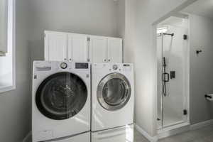 Washroom with light tile patterned floors and washer and dryer