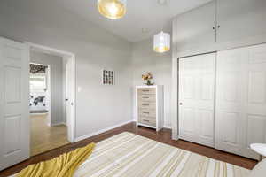 Unfurnished bedroom featuring dark wood-type flooring, vaulted ceiling, and a closet