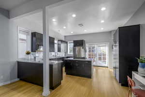 Kitchen featuring stainless steel appliances, sink, tasteful backsplash, light wood-type flooring, and french doors