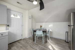 Dining area featuring ceiling fan, light wood-type flooring, and lofted ceiling