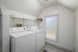 Laundry room with washer and clothes dryer, a wealth of natural light, and light hardwood / wood-style floors