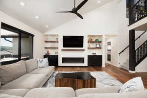 Living room featuring high vaulted ceiling, dark wood-type flooring, and ceiling fan