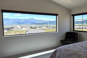 Carpeted bedroom featuring a mountain view, multiple windows, and lofted ceiling