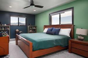 Carpeted bedroom featuring multiple windows and ceiling fan