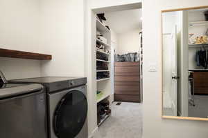 Washroom with light carpet and washing machine and clothes dryer