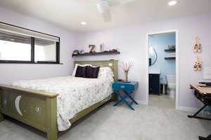 Carpeted bedroom featuring ceiling fan and ensuite bath