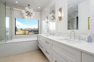 Bathroom with shower with separate bathtub, vanity, and an inviting chandelier