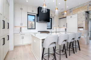 Kitchen featuring pendant lighting, white cabinets, and a kitchen island with sink