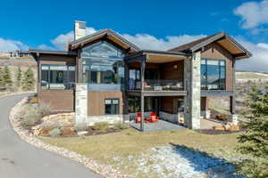 Rear view of house with a yard, a balcony, and a patio area