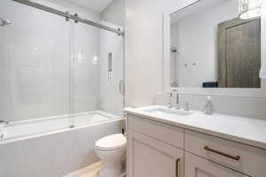 Full bathroom with toilet, combined bath / shower with glass door, and vanity