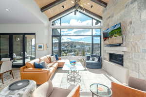 Living room with wood ceiling, a large fireplace, high vaulted ceiling, and beam ceiling