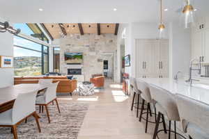 Dining room with a fireplace, beam ceiling, wood ceiling, sink, and light hardwood / wood-style flooring