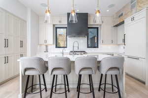 Kitchen featuring white cabinetry, light wood-type flooring, and a center island with sink