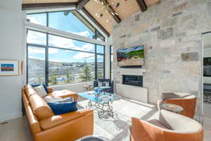 Living room with a stone fireplace, high vaulted ceiling, hardwood / wood-style floors, beamed ceiling, and wooden ceiling