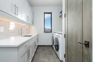 Laundry area with cabinets, separate washer and dryer, sink, and dark tile patterned floors