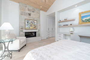 Bedroom featuring light hardwood / wood-style floors, wooden ceiling, high vaulted ceiling, a closet, and a fireplace