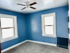 Carpeted empty room featuring ceiling fan and a healthy amount of sunlight