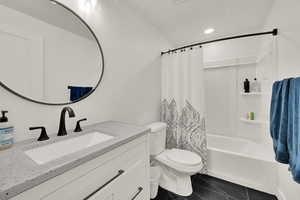 Full bathroom featuring toilet, shower / bath combo with shower curtain, vanity, and tile patterned flooring