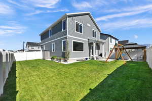 Rear view of property featuring a patio area, a lawn, and a playground