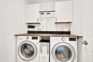 Washroom with cabinets and washer and clothes dryer