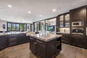 Kitchen featuring stainless steel microwave, tasteful backsplash, a center island, light hardwood / wood-style flooring, and sink