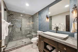 Bathroom with a shower with door, toilet, vanity, and tile patterned flooring