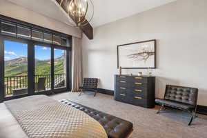 Bedroom with access to outside, carpet, and an inviting chandelier