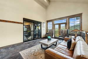 Carpeted living room featuring high vaulted ceiling and french doors