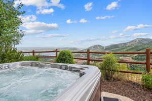 Wooden deck with a hot tub and a mountain view