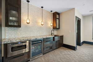 Kitchen with stainless steel oven, pendant lighting, wine cooler, sink, and backsplash