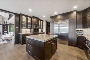 Kitchen featuring black appliances, backsplash, light wood-type flooring, and a center island