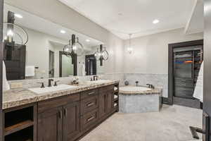 Bathroom with double sink vanity, tiled bath, and tile patterned flooring