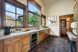 Kitchen with stainless steel microwave, tasteful backsplash, beverage cooler, light stone counters, and sink