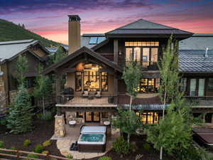 Back house at dusk featuring a balcony and a patio area