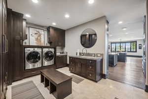 Laundry area featuring cabinets, sink, independent washer and dryer, and light hardwood / wood-style floors