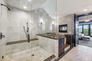 Bathroom with an enclosed shower, tile walls, an inviting chandelier, and a fireplace