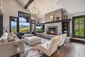 Living room featuring a large fireplace, beam ceiling, wood-type flooring, and a healthy amount of sunlight