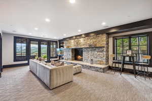 Carpeted living room with a stone fireplace and a wealth of natural light