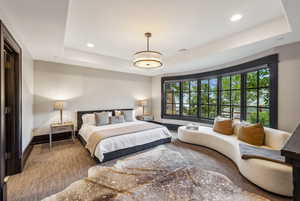 Carpeted bedroom with a tray ceiling