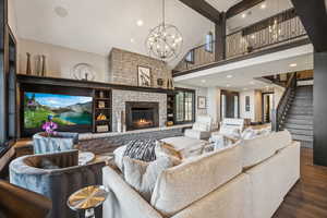 Living room with high vaulted ceiling, dark hardwood / wood-style flooring, a chandelier, and a stone fireplace